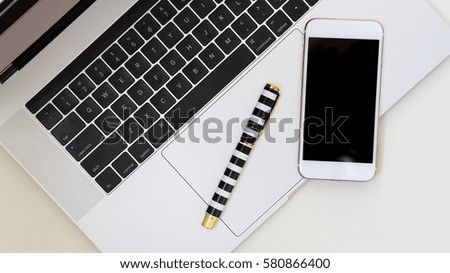 Working Lay flat Laptop with smart phone and pen from above