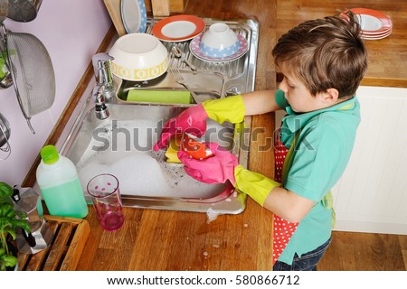 Kids helping with the chores at home, doing the dishes in the kitchen Royalty-Free Stock Photo #580866712