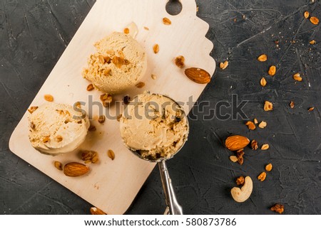 Home made caramel nut ice cream spoon and balls on the kitchen board, on a stone gray table  Royalty-Free Stock Photo #580873786