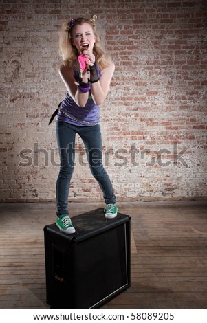 Young punk rocker on a speaker in front of a brick background