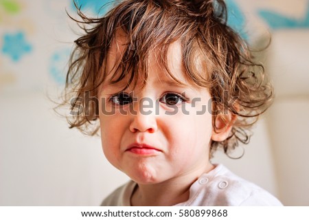 Portrait of a cute little toddler boy kid curly hair smiling and crying fun face expression Royalty-Free Stock Photo #580899868
