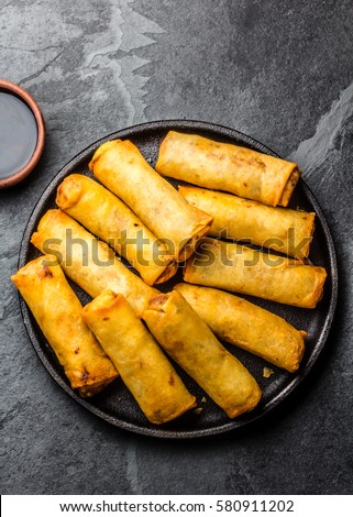 Fried spring rolls on black iron plate on grey stone slate background. Top view Royalty-Free Stock Photo #580911202