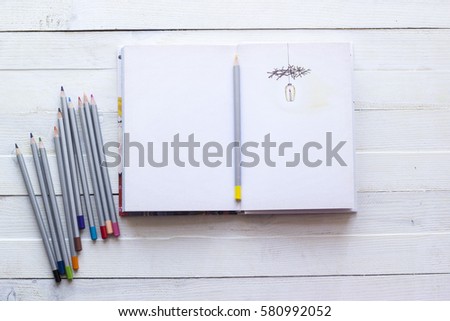 Pencils and paper notebook for creativity, art, notes and drawing on a white wooden background