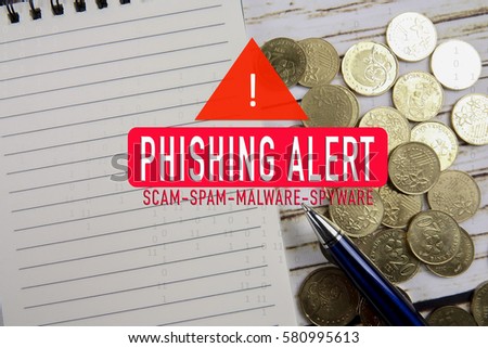 Phishing alert conceptual with laptop and coins on wooden.