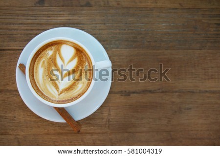 Cup of hot latte art with cinnamon coffee on wooden table   