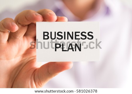 Closeup on businessman holding a card with text BUSINESS PLAN, business concept image with soft focus background