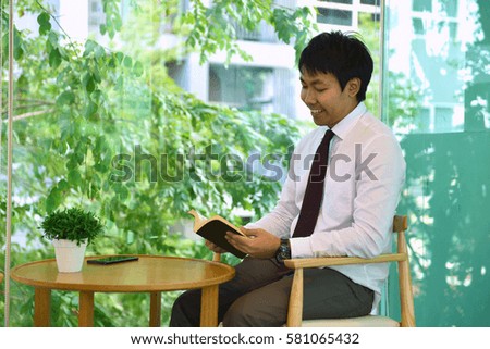 An Asian business man reading a book, person smiling
