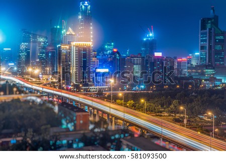 light trails on city street with cityscape at night in China.