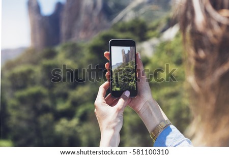 Hipster girl making photo on smart phone mobile closeup, view tourist hands using gadget phone in travel on background mountains and landscape; finger touch screen cellphone mock up nature, templates