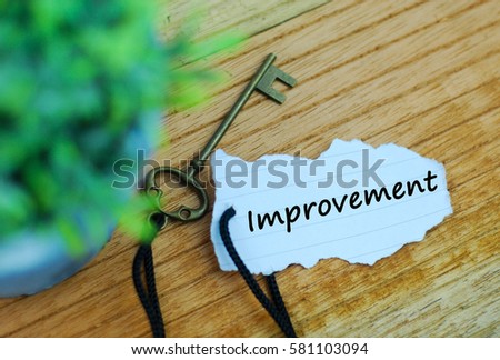 Key and torn paper with text improvement on wooden background