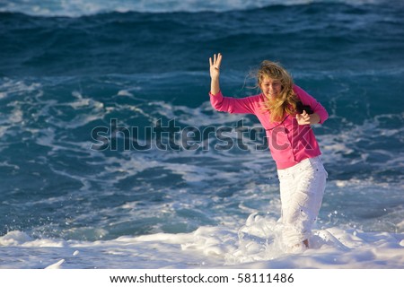 A happy young woman with long blond hair she lost her balance in the surf. Horizontal picture and lots of space left.