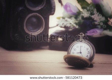 Close up pocket watch and camera on wood table, process vintage tone