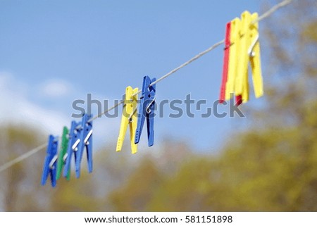 Colorful clothes pins on rope. Art concept on blurred country house background