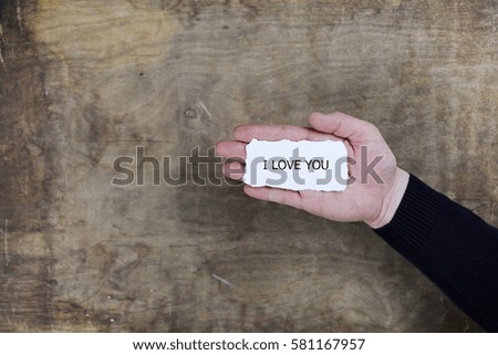 male hands holding a white blank sheet of paper on the background of wooden texture table