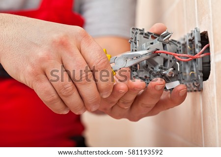 Electrician mounting the wires into electrical wall fixture or socket - closeup on hands and pliers Royalty-Free Stock Photo #581193592