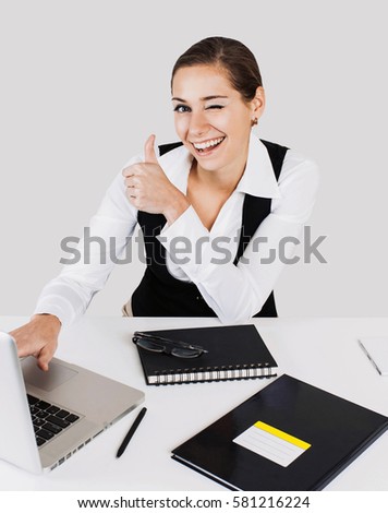 Portrait of a young beautiful business woman showing thumb up sign, over gray background
