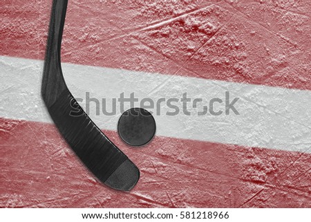 Hockey puck, stick, and the image of the Latvian flag on the ice. Concept