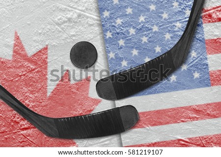 Hockey puck, hockey sticks and a picture of the Canadian and the American flag on the ice. Concept