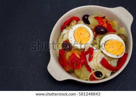 cod fish with potato, red pepper, egg and olives on plate