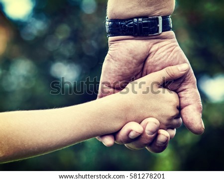 Toned Photo of Adult and Kid Hands on the Nature Background closeup