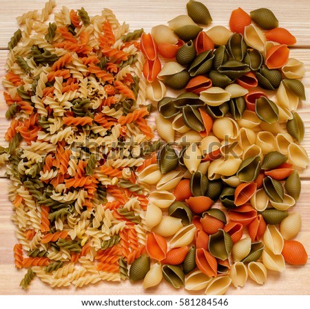 Assortment of colorful pasta in  on wooden background