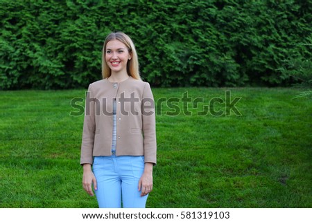 Women with blond hair european appearance smiles and removed advertising for clothes and accessories, women's magazine or waiting for friend. Girl dressed in bright light blouse, beige jacket and blue