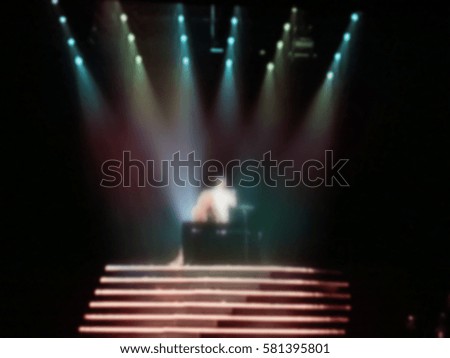 Blurs the image. Bright spotlights illuminated the scene during a musical concert. Multi-colored rays.