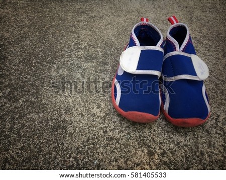 Blue sneaker for kid on dirty concrete floor