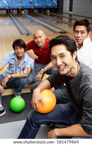 Four men in bowling alley, smiling at camera