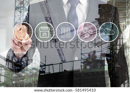 Crane and building construction site against midsection of businessman touching icon interface