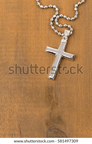 Silver cross with necklace on wooden background