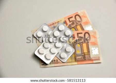 Euro banknote and pills on white background. Symbolizing health care costs in European Union. 