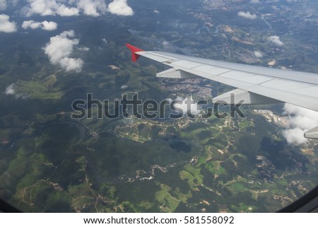 Wing of an airplane flying above the city. The view from an airplane window. Cloudy and color sky. Photo applied to tourism operators. picture for add text message or frame website. Traveling concept.