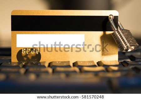 Gold credit card with small hanging padlock on keyboard closeup