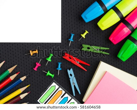 school supplies pencils, markers, buttons, colored paper on a black background