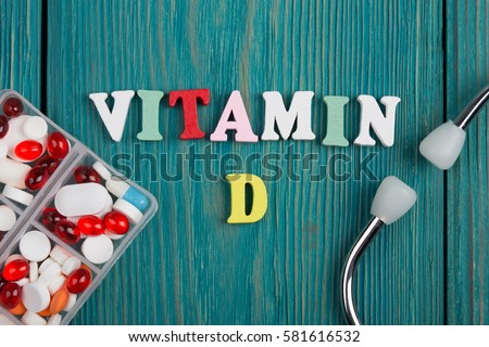 Text "Vitamin D" of colored wooden letters, stethoscope and pills on a blue wooden background Royalty-Free Stock Photo #581616532