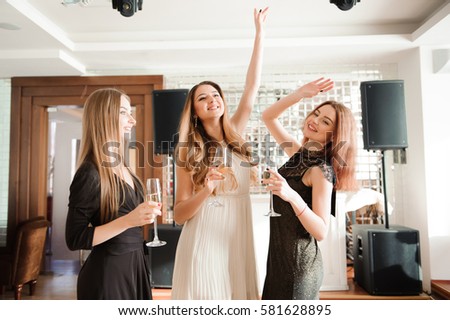 Portrait of smiling friends holding glass of champagne while dancing at bar