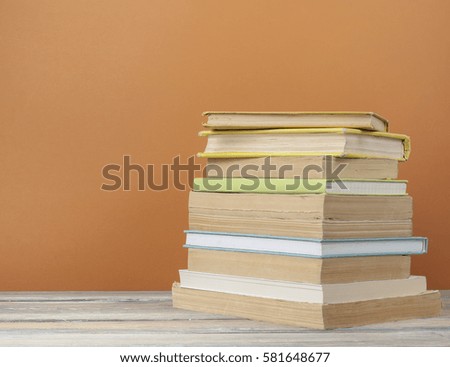 Stack of books on wooden table on colorful wall background. Education background.