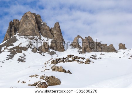 Jagged cliffs and blue sky with clouds. L'Aiguille Percee or Eye of the Needle is a spectacular rock formation as arch in the French Alps, near Tignes.