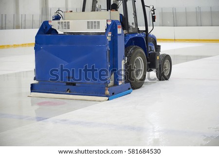 Resurfacing machine cleaning ice hockey rink.