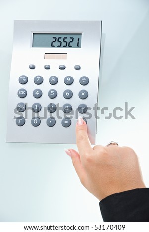 Closeup of female hand pushing key on digital calculator.