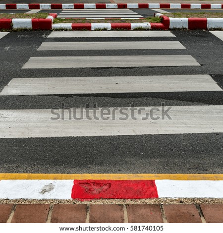 Empty crosswalk on asphalt road with red and white sign on sidewalk curb