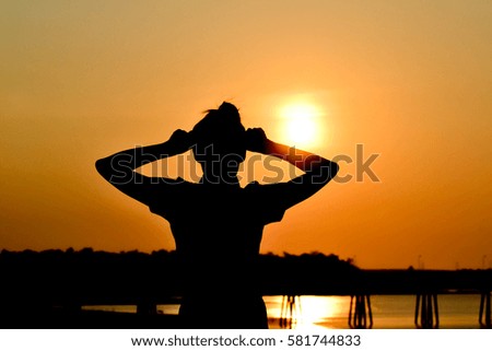 Women standing with hand on head in the evening with sunset