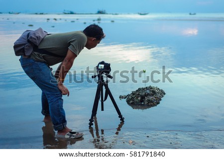 photographer takes pictures at sunset with tripod