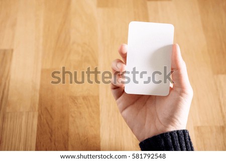 Woman holding blank business card for mock up, present over wooden desk background