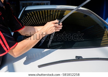Man is changing windscreen wipers on a car, Asian man installing new windshield wipers by himself at home Royalty-Free Stock Photo #581812258