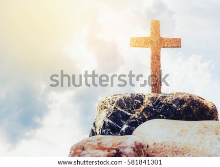 wooden cross on the rock against cloudy sky background