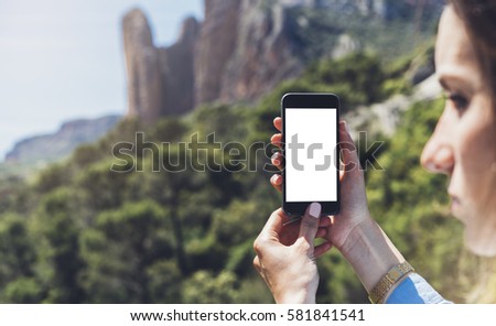 Hipster girl making photo on smart phone mobile closeup, view tourist hands using gadget phone in travel on background mountains landscape; finger touch screen cellphone mock up nature, templates
