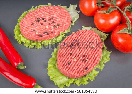 Raw burgers with lettuce on a gray background. Tomatoes, peppers chilli