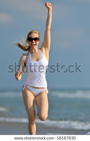 lovely blonde female running along atlantic ocean and waving